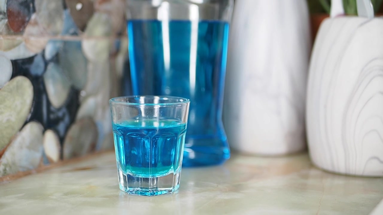 Piccolo bicchiere di collutorio blu sul bancone del bagno
