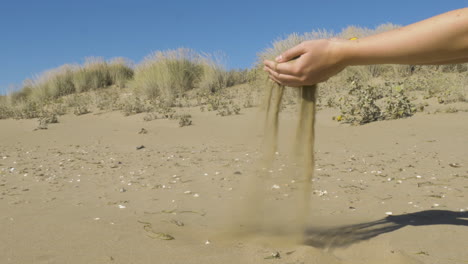 Taking-sand-from-a-beach-and-let-it-slip-through-the-fingers-back-to-the-beach