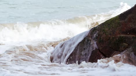 las olas de la marea oceánica golpean las rocas y el niño evita que la escena camine frente a la cámara