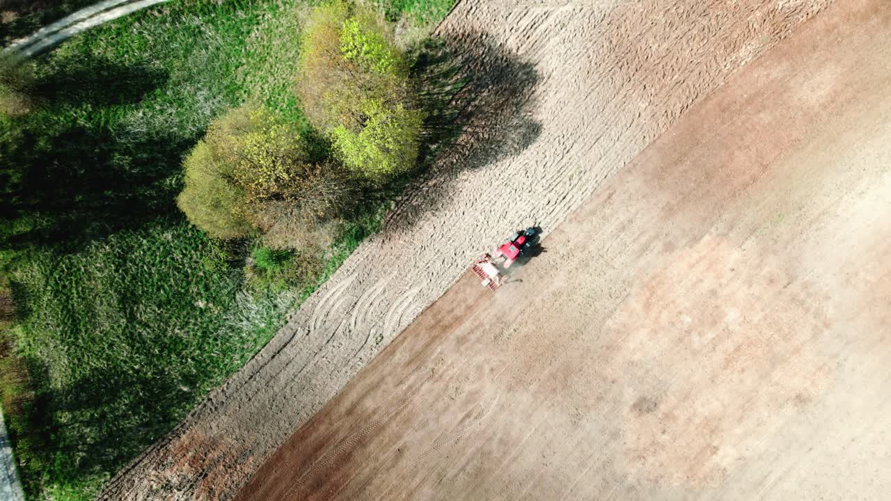 A tractor working in a field next to a green forest