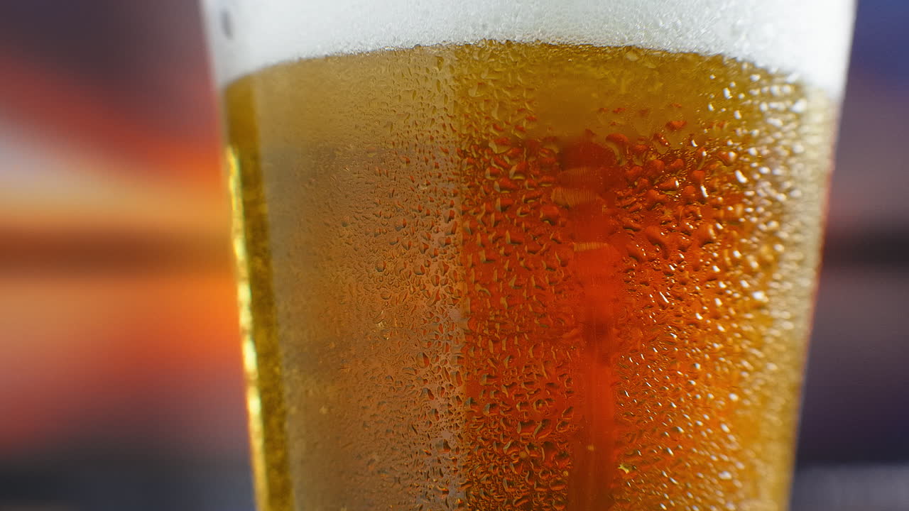 close-up cámara lenta: cerveza fría en un vaso grandes gotas y burbujas en la cerveza