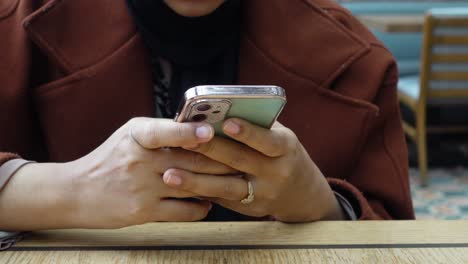 mujer sentada en una mesa usando su teléfono
