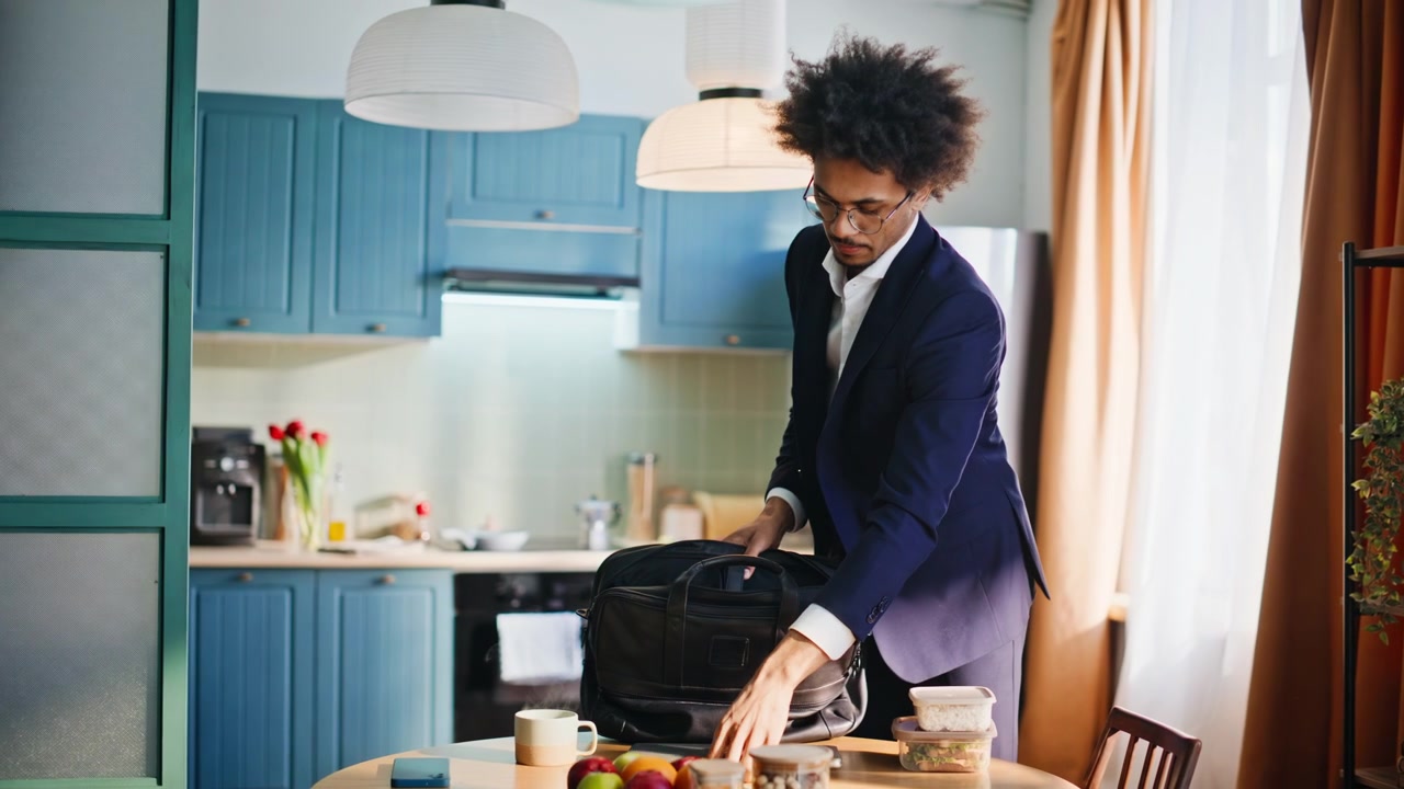 Businessman packing briefcase morning kitchen. Man preparing work lunch home.