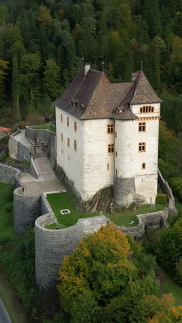 vertical, aerial: valangin castle during the day in canton of neuchatel, switzerland, establishing drone shot
