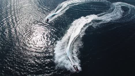 couple of jet ski scooters on fast ride on tropical sea water surface, birdseye aerial view