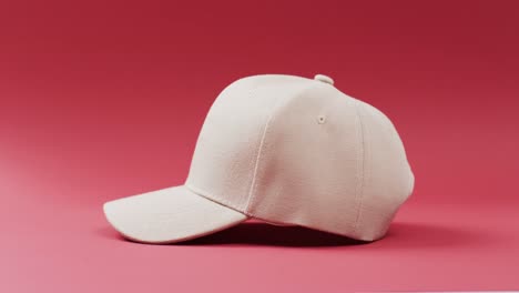 Video-of-beige-baseball-cap-and-copy-space-on-red-background