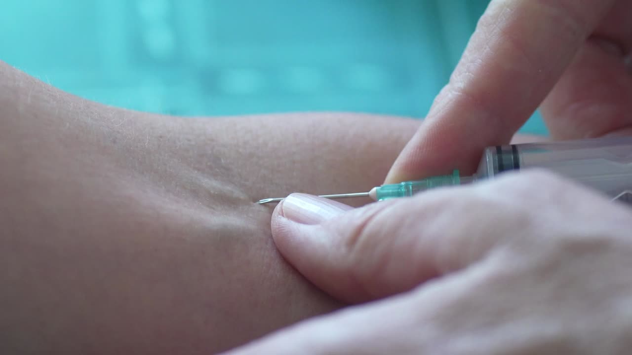 Close-up of a biochemist's hands taking a blood sample from a woman's arm