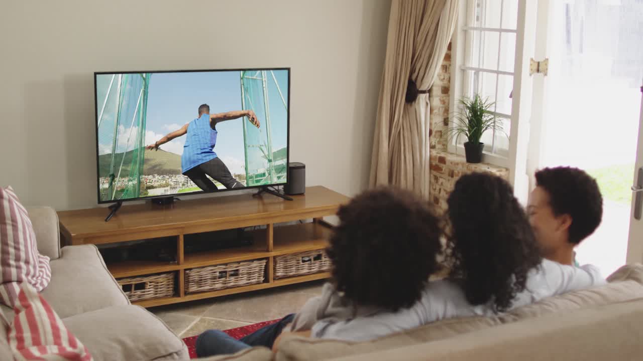 Composizione di famiglia felice seduta insieme a casa che guarda un evento di atletica leggera di lancio del disco in TV.