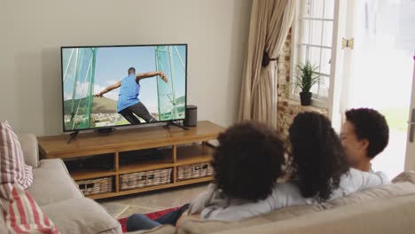 Compuesto-De-Familia-Feliz-Sentados-Juntos-En-Casa-Viendo-Un-Evento-De-Atletismo-De-Disco-En-La-Televisión