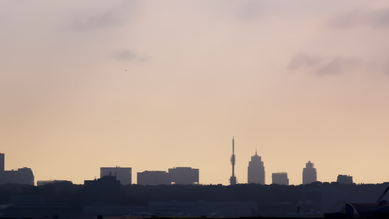 Avión volando sobre el horizonte de la ciudad al amanecer/atardecer