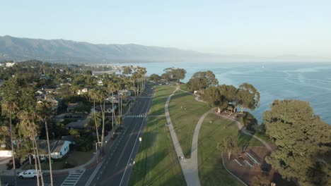 antena de gran altitud sobre el parque de la ciudad costera durante la puesta de sol con árboles y el océano pacífico con montañas en el fondo, en santa barbara, california, ee.uu.