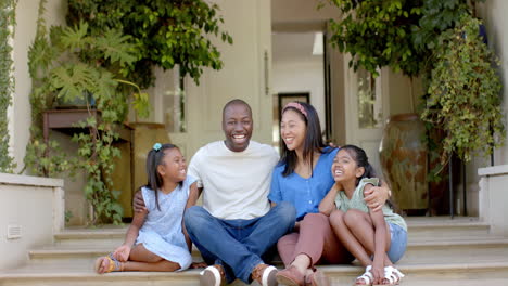 smiling family of four sitting on porch steps, enjoying time together