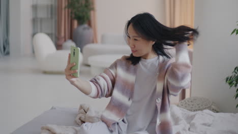 woman taking selfie in cozy bedroom