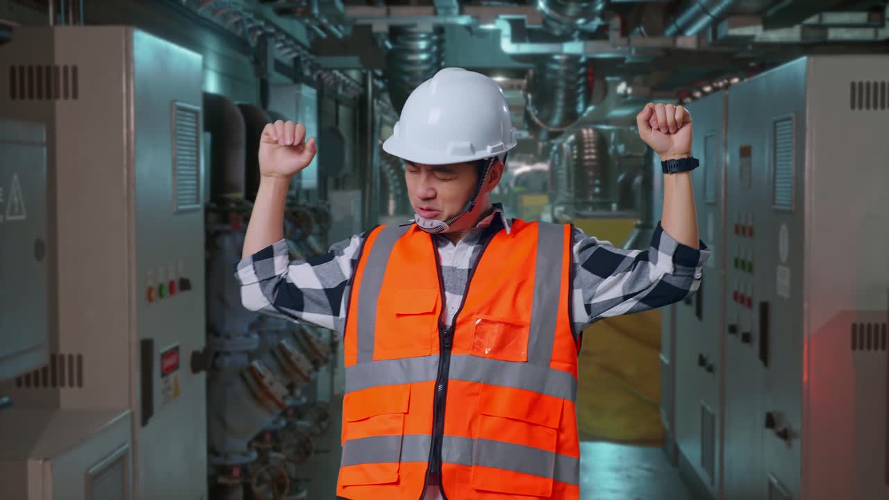 Asian Male Engineer With Safety Helmet Screaming Goal And Dancing Celebrating In Engine Control Room, Work Of Electrical Generators