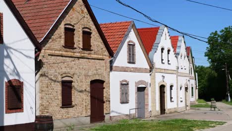 A-shot-of-the-picturesque-Wine-Village-Hajos-in-Hungary,-featuring-five-white-houses-with-red-roofs-and-wooden-doors,-along-with-one-beige-house-also-with-wooden-doors