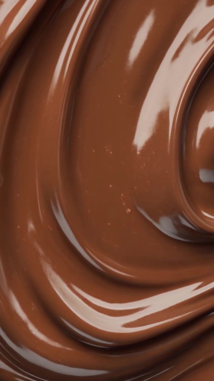 Macro ravvicinato di una densa crema al cioccolato al latte che si avvolge in profonde pieghe curve