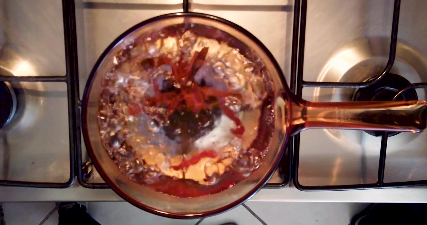 Ripresa zenitale di acqua con cannella sul fornello, in procinto di bollire, come parte della routine per preparare tè o caffè per la colazione.