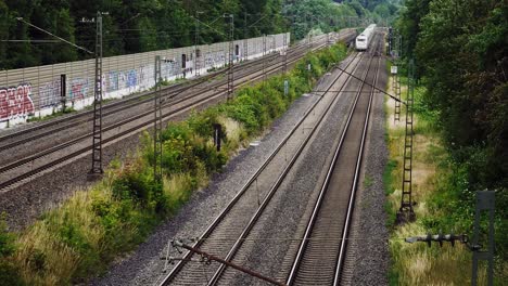 un tren blanco pasa por debajo de una serie de líneas eléctricas en un sistema ferroviario de cuatro vías