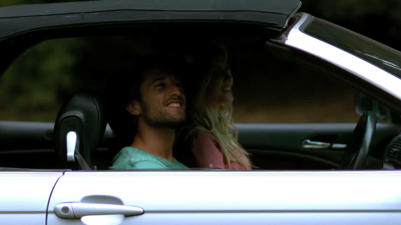 una pareja sonriendo y mirando el coche.