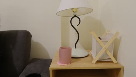 disparo estático medio de una chica colocando una taza en un coaster y agarrando el control remoto de la televisión