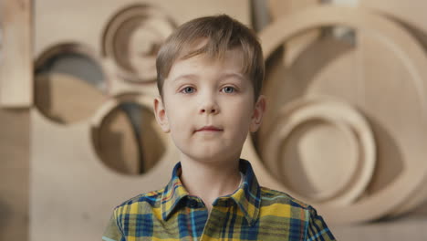 retrato de niño rubio mirando a la cámara y sonriendo en el taller de carpintería