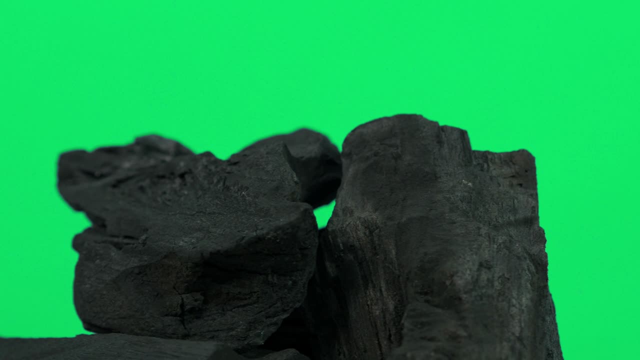 carbón de madera. madera natural o carbón negro tradicional en bucle en giratorio. fondo de pantalla azul o verde con luz led de color. disparo en estática. carbón para cocinar en la parrilla de la barbacoa. carbón negro.