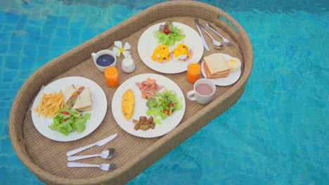 Luxury-floating-snacks-tray-on-pool-transparent-water,-dishes,-drinks
