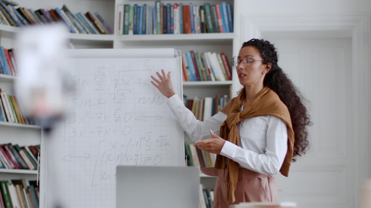 Woman teaching mathematics online from a home library