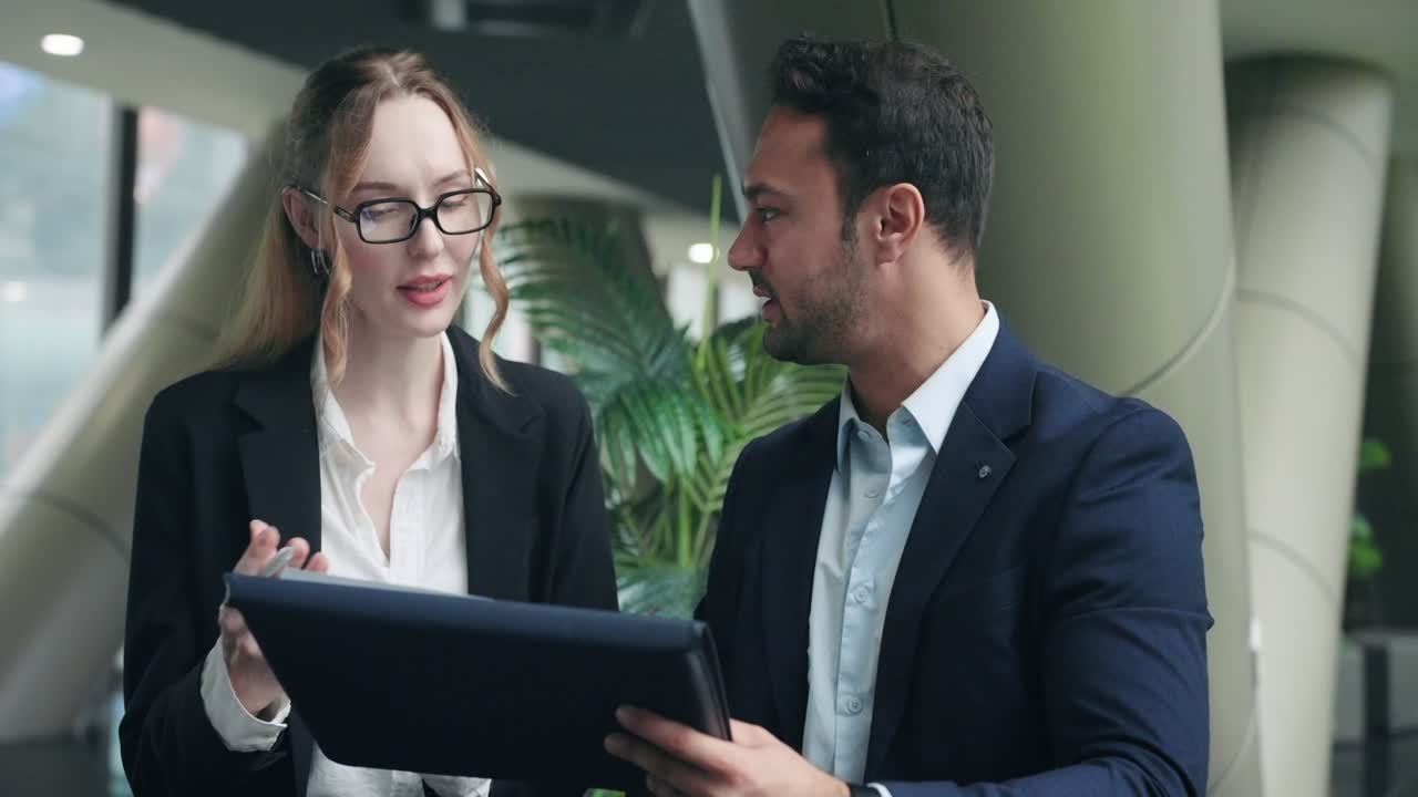 Professional businessman and businesswoman work on a business plan and review statistical papers together while discussing improvements in modern corporate office