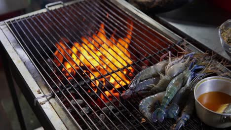 raw jumbo river prawns ready to cook over a flaming grill with a side of melted butter to enhance taste