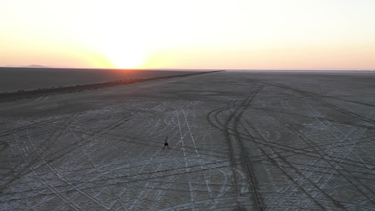Aerial View of Man Walking on Barren Landscape Patterns of Bonneville Salt Flats in Twilight Above Utah USA