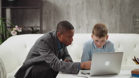 Black-teacher-explains-educative-materials-on-laptop-to-boy