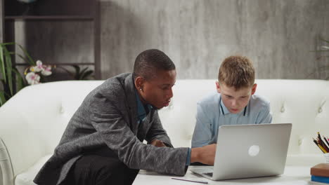 black teacher explains educative materials on laptop to boy