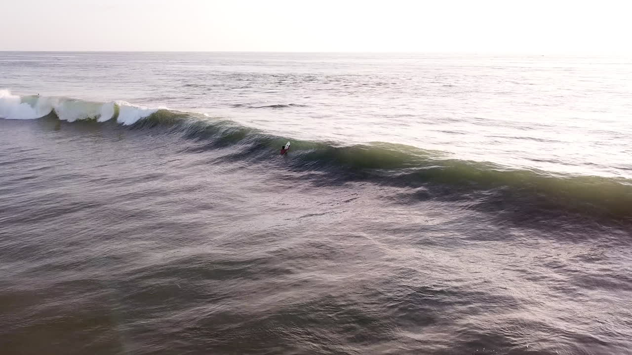 gente surfeando en la playa ondulada de olón en ecuador al atardecer- antena
