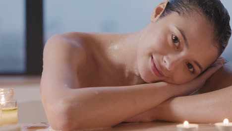 close up view of woman leaning on a wooden table smiling at camera while taking a bath