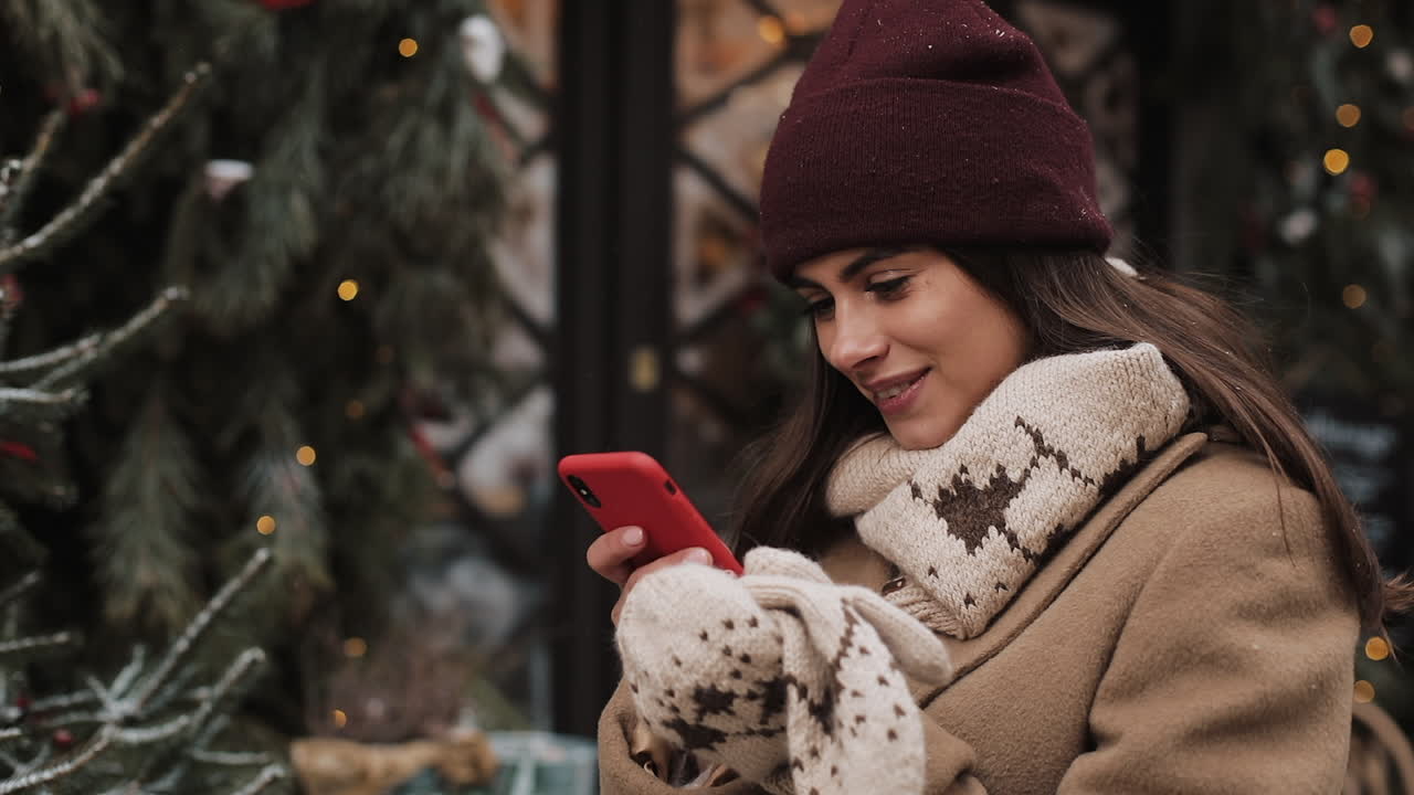 Woman in winter attire using her phone outdoors at Christmas