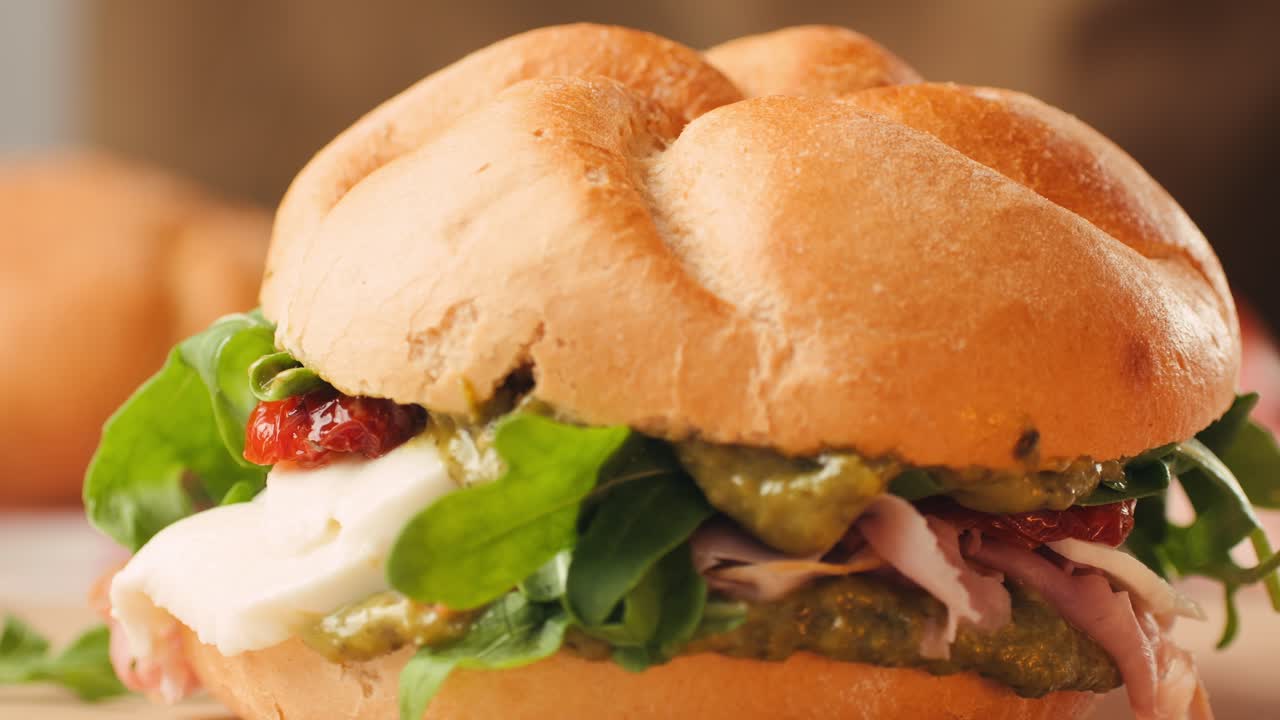 Mortadella ham sandwich, Traditional italian focaccia filled with thin pesto slices of mortadella, served by chef man in cafe restaurant. Macro of traditional italian spanish tapas antipasti.