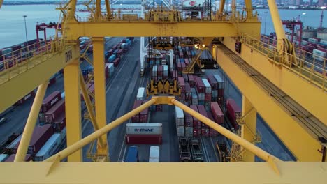 cranes efficiently load containers onto ships in a bustling port as the sun sets, casting warm tones over the shipping yard. the scene captures industry and transportation in action.