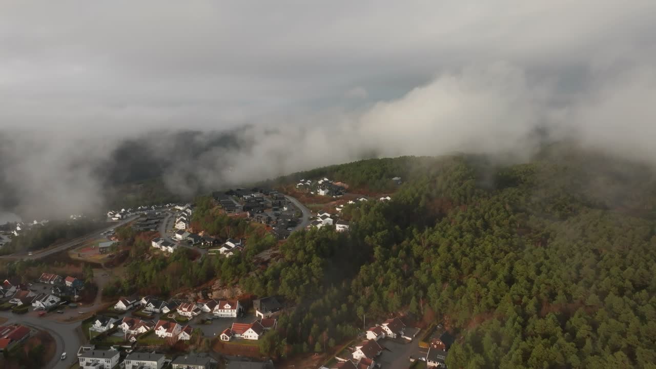 Imagens de drone de um conjunto habitacional na Noruega com névoa flutuando no ar e o sol iluminando as nuvens.
