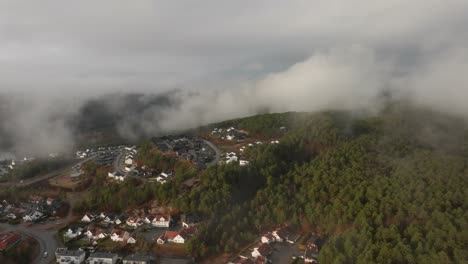 drone footage of housing estate in norway with some fog floating in th air and sun lighting up the clouds