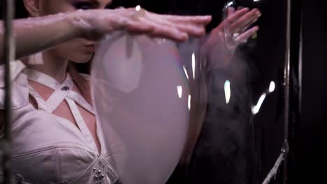 close-up: girl does tricks with soap bubbles. she takes two big bubbles with her hands, then turns them into smoke