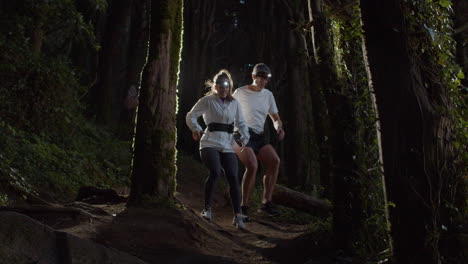 Runners-having-break-while-running-on-forest-trail-at-night