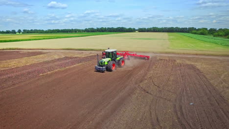 Agricultural-tractor-with-trailer-plowing-on-rural-field.-Farming-industry