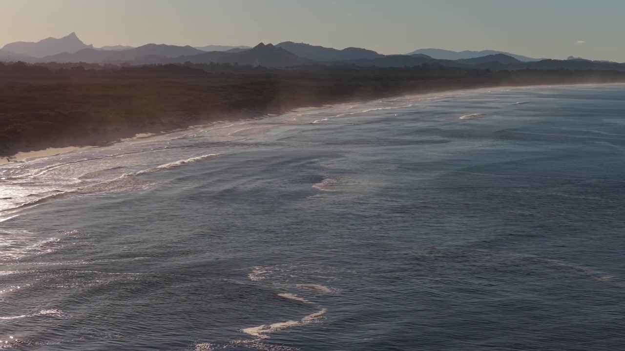 Costa di Belongil Beach con onde spumeggianti al tramonto - Byron Bay, NSW, Australia. - Ripresa aerea.