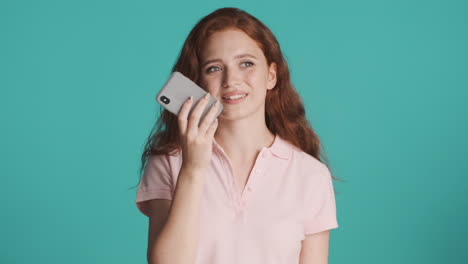 redheaded girl in front of camera on turquoise background.