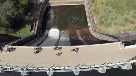 bird's eye view of mattupetty dam and crossing tourists near munnar in south india - aerial top view tilt up reveal