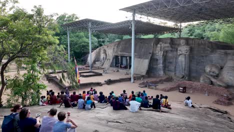 visitors gather to admire the ancient buddha statues at uththararamaya, a rock temple in polonnaruwa, showcasing cultural heritage and historical significance.