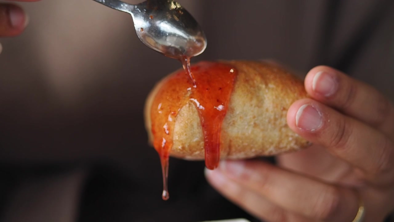 Marmellata rossa dolce che cola su un panino dorato.