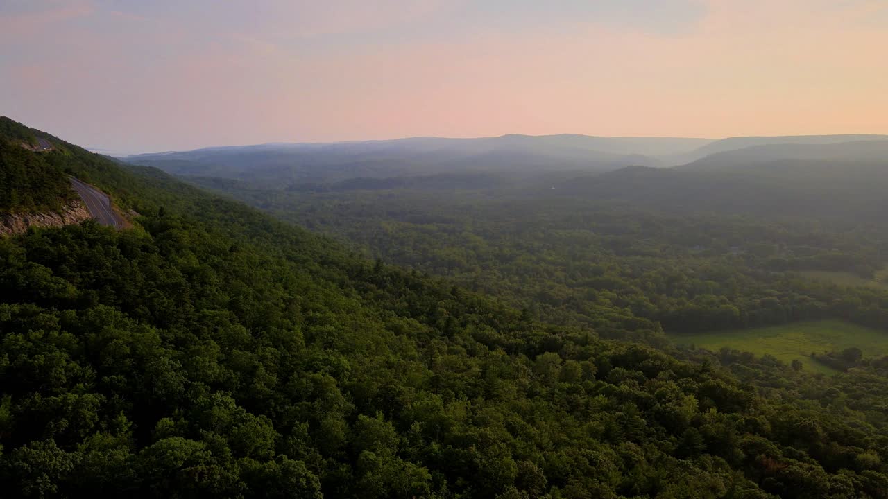 Aerial drone video footage of a golden hour summer sunset in a green, vibrant rural Appalachian Mountain valley with beautiful light. In particular, this is in New York's Hudson Valley