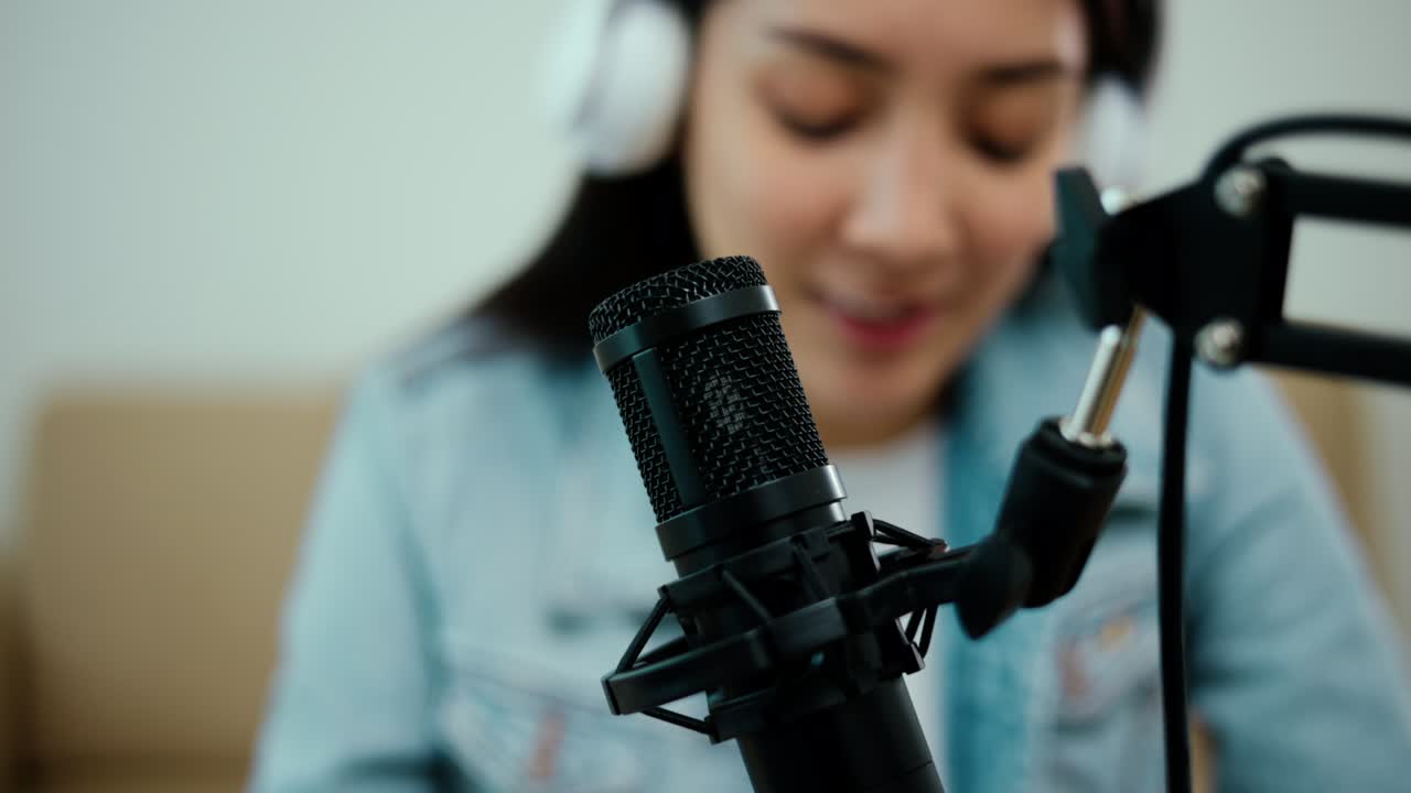Close-up condenser microphone of content creator woman host streaming his a podcast on laptop with headphones interview conversation at home broadcast studio. Blogger recording voice over radio.